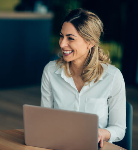 Woman Smiling While Using Laptop