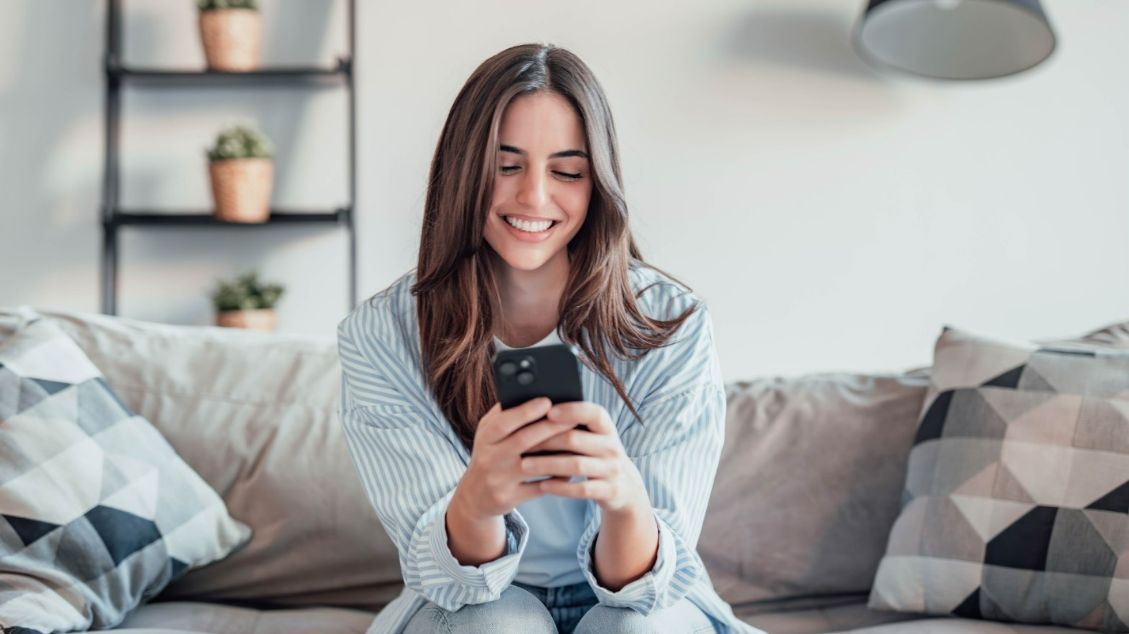 Woman Smiling While Looking at Her Phone